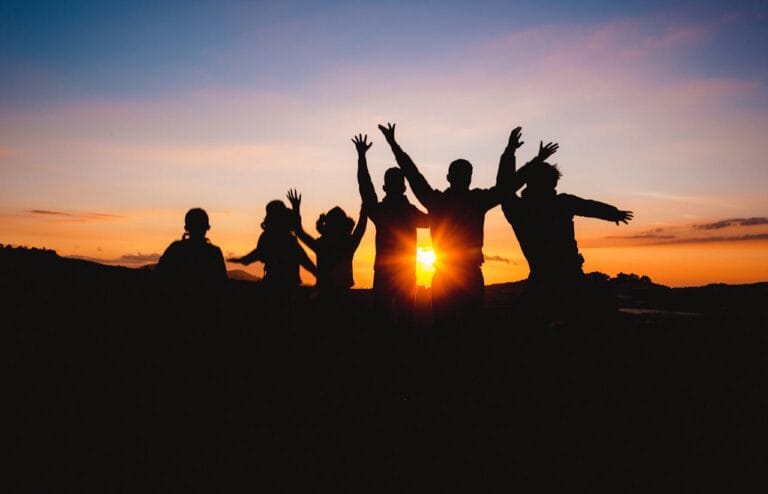 Silhouettes of people jumping on a beach at sunset, symbolizing freedom and presence